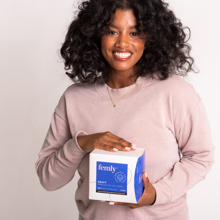 Black woman holding femly's 100% organic cotton heavy menstrual pads.